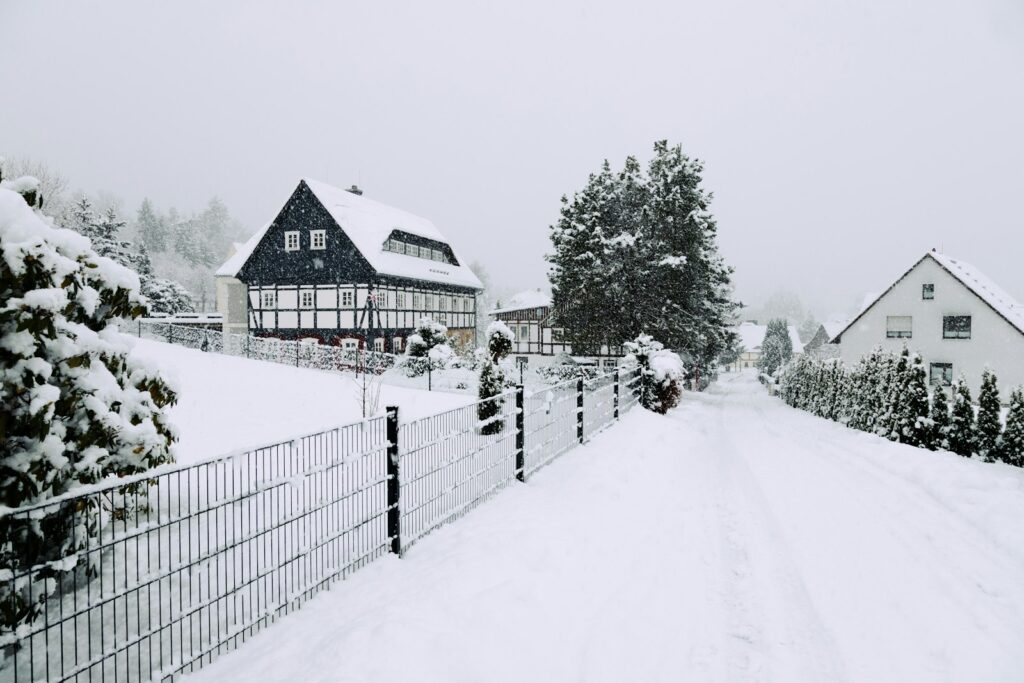 A snow covered road next to a fence