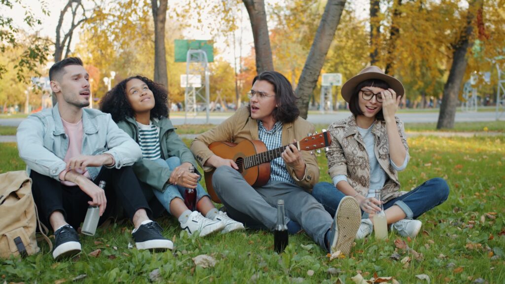 Four friends relaxing in a park with a guitar