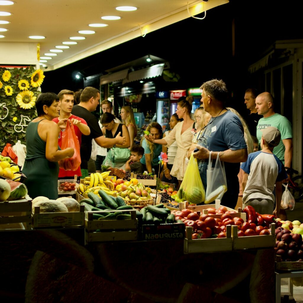 A group of people standing around a table filled with fruits and vegetables