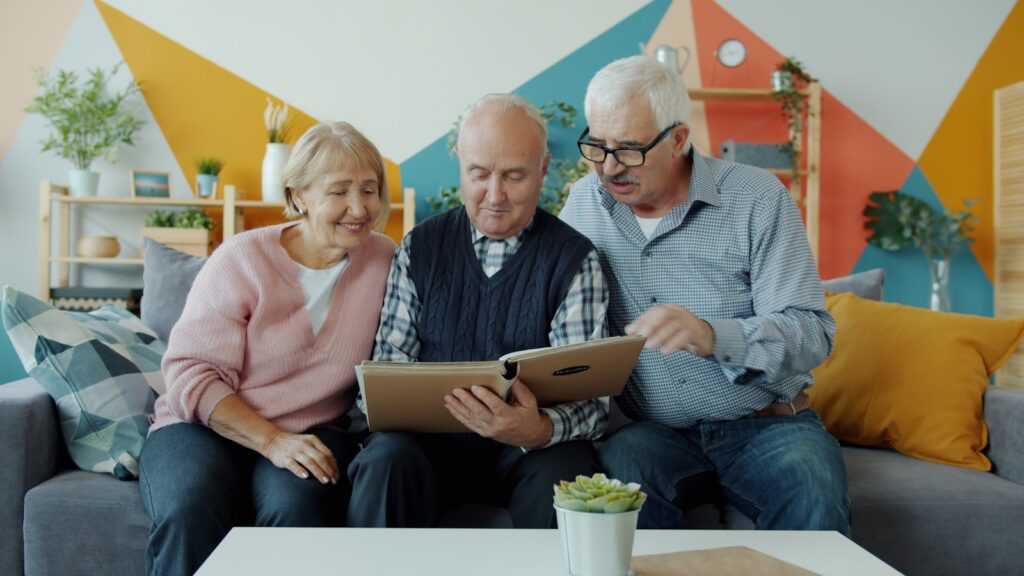 Three seniors looking at a photo album together.