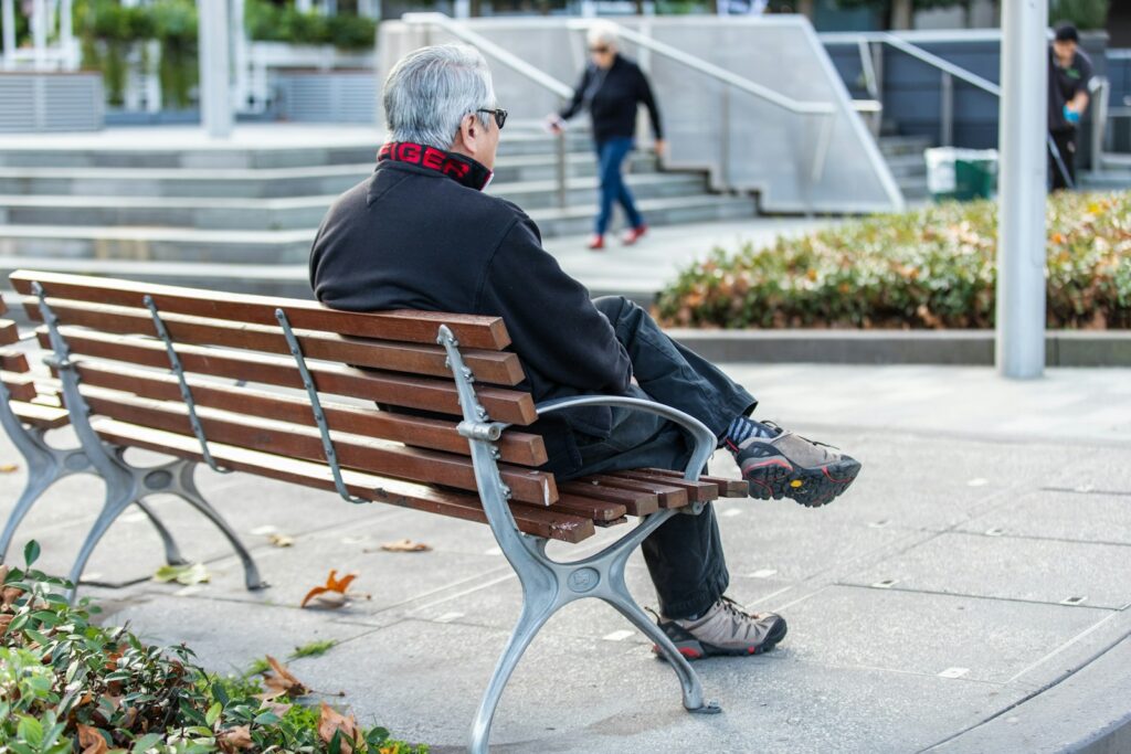 man in black jacket sitting on bench