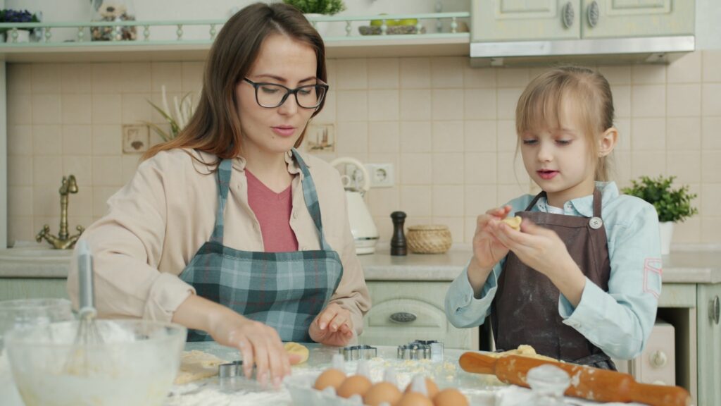Woman and child baking cookies in a kitchen.