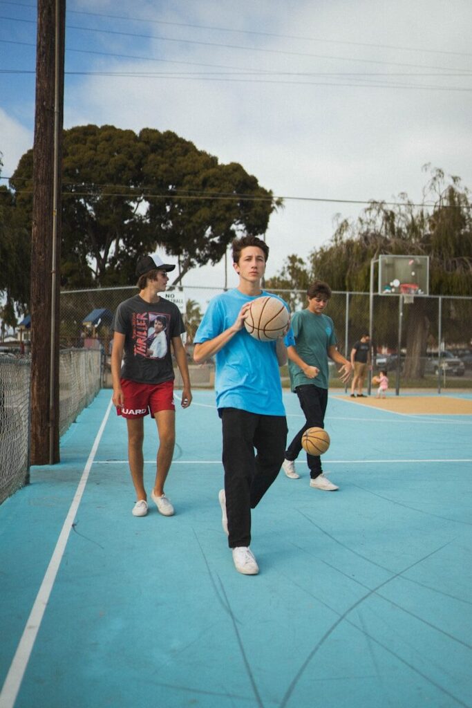 man wearing blue t-shirt and black pants holding basketball during daytime