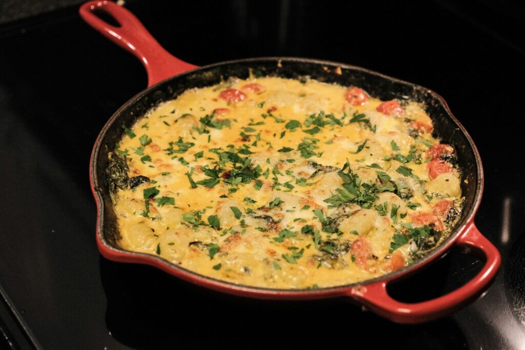 a red pan filled with food sitting on top of a stove